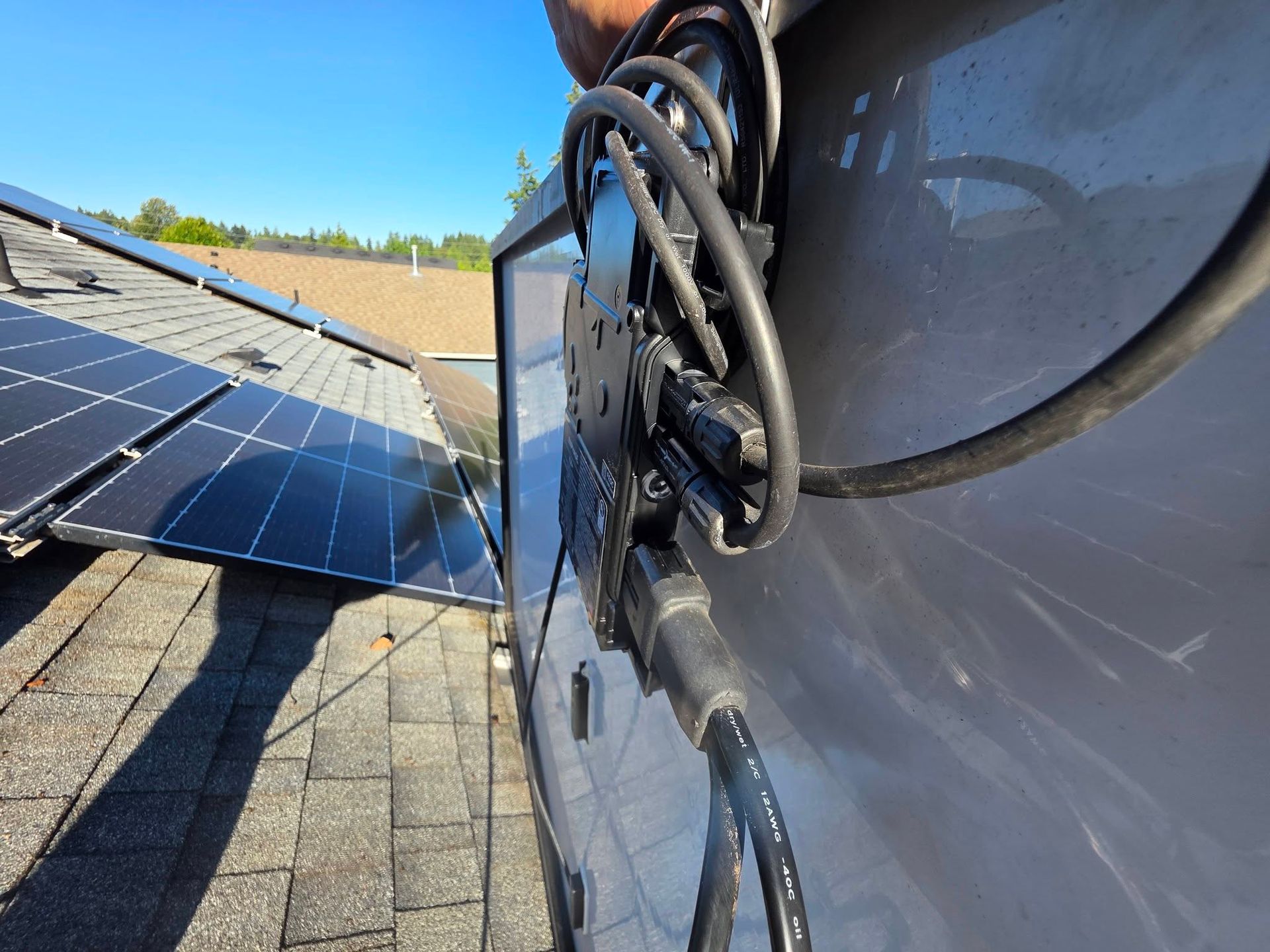 Solar panels mounted on a rooftop beside a close-up of black cables and gray equipment box