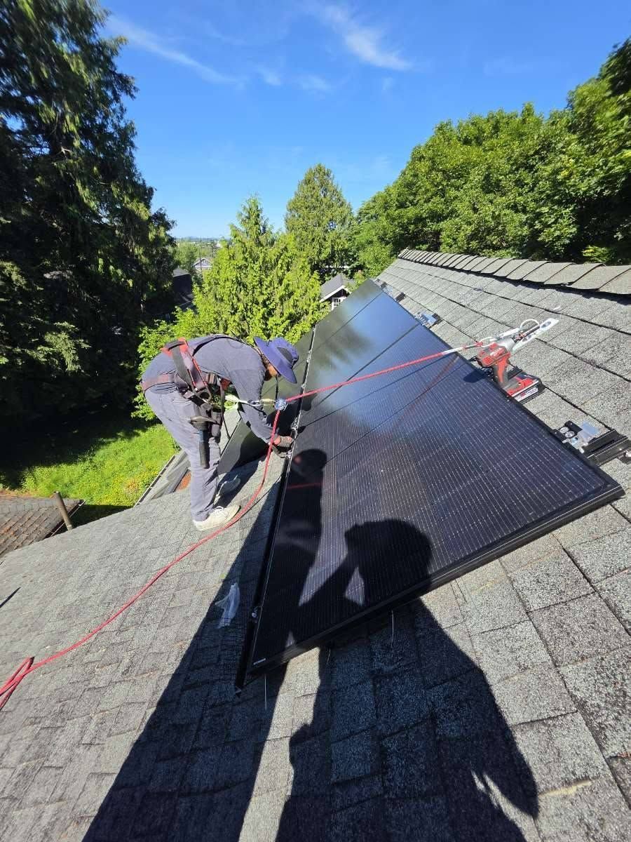 Workers installing solar panels on a sloped roof on a sunny day
