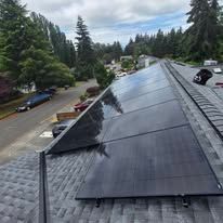 Solar panels installed on a residential roof in a wooded neighborhood.