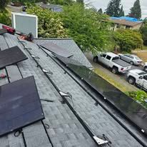 Rooftop with solar panels and mounting rails overlooking parked cars and trees