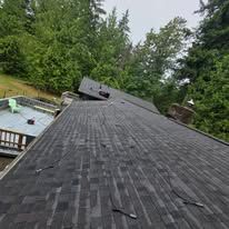 Damaged shingled roof with a bent vent, viewed from the rooftop beside trees and a pool