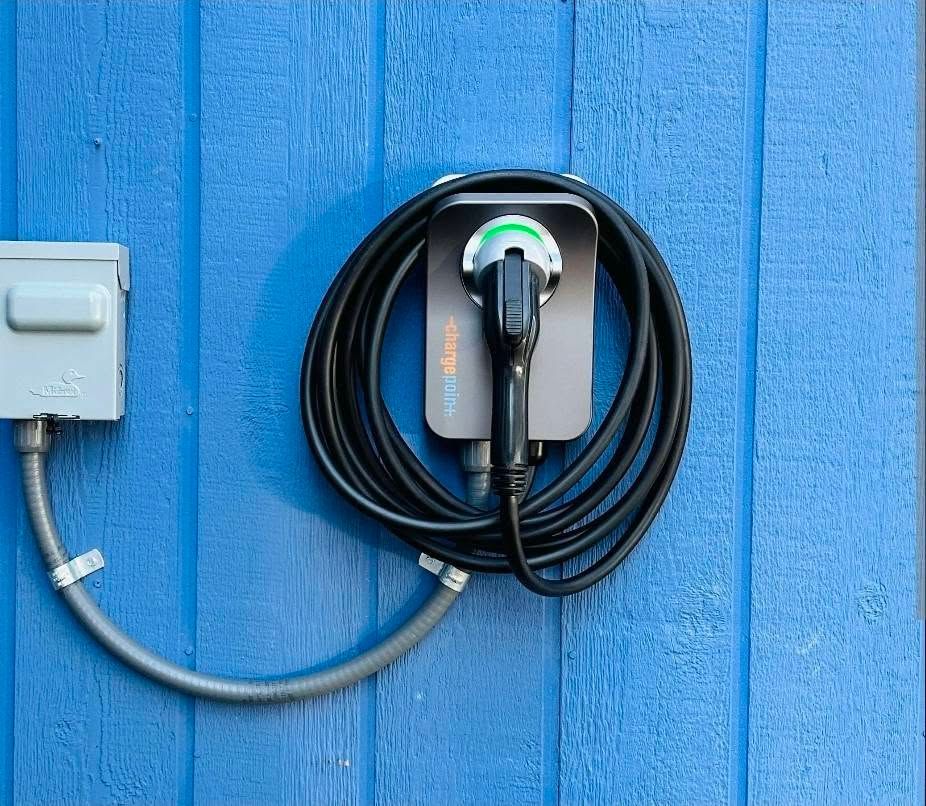 Electric vehicle charging station with coiled cable mounted on a blue wall.