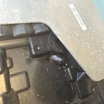 Close-up of a dusty black device under a beige desk, with a cable and chair leg visible