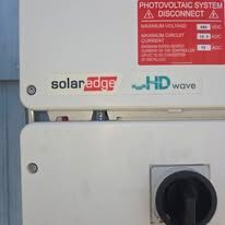 SolarEdge photovoltaic system disconnect box with red warning label and black rotary switch
