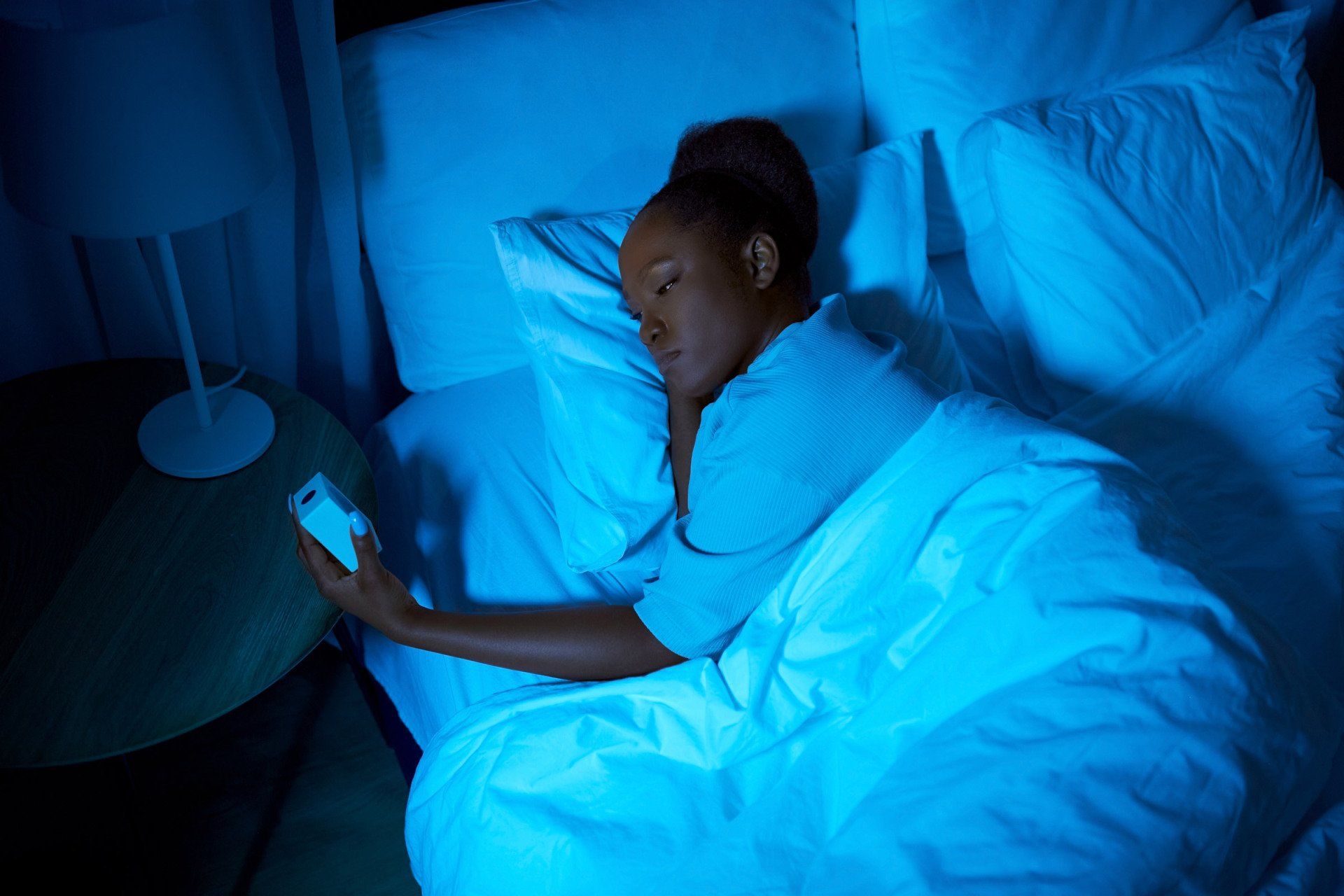 Woman lying in bed staring at clock