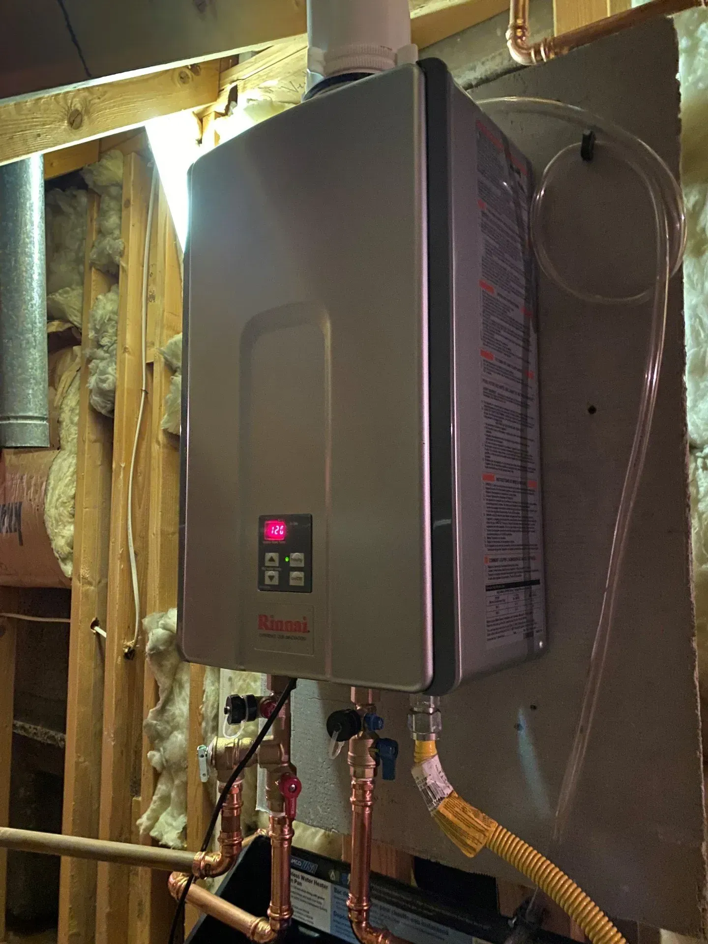 A stainless steel water heater is hanging on a wall