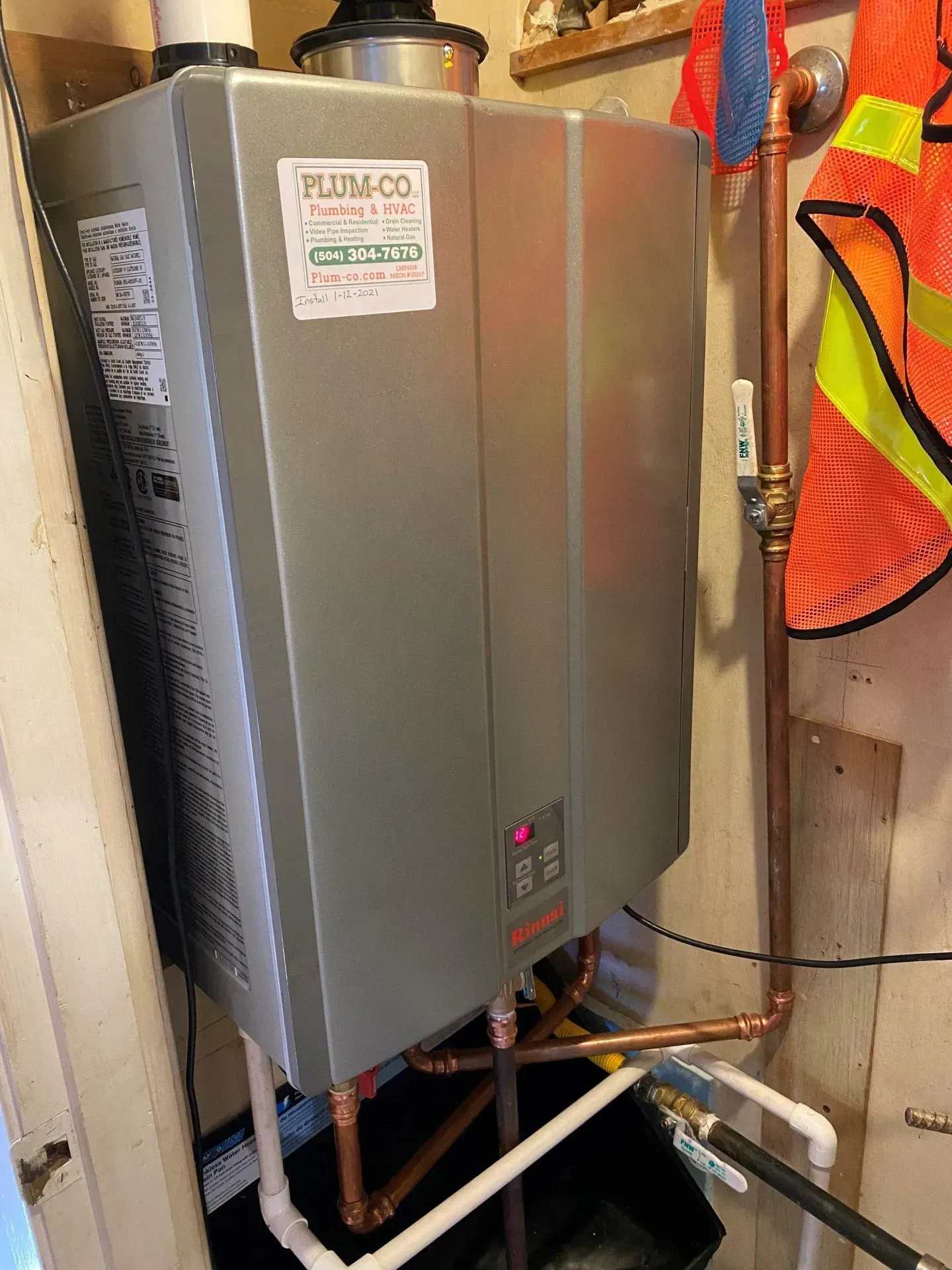 A water heater is sitting in a room next to pipes