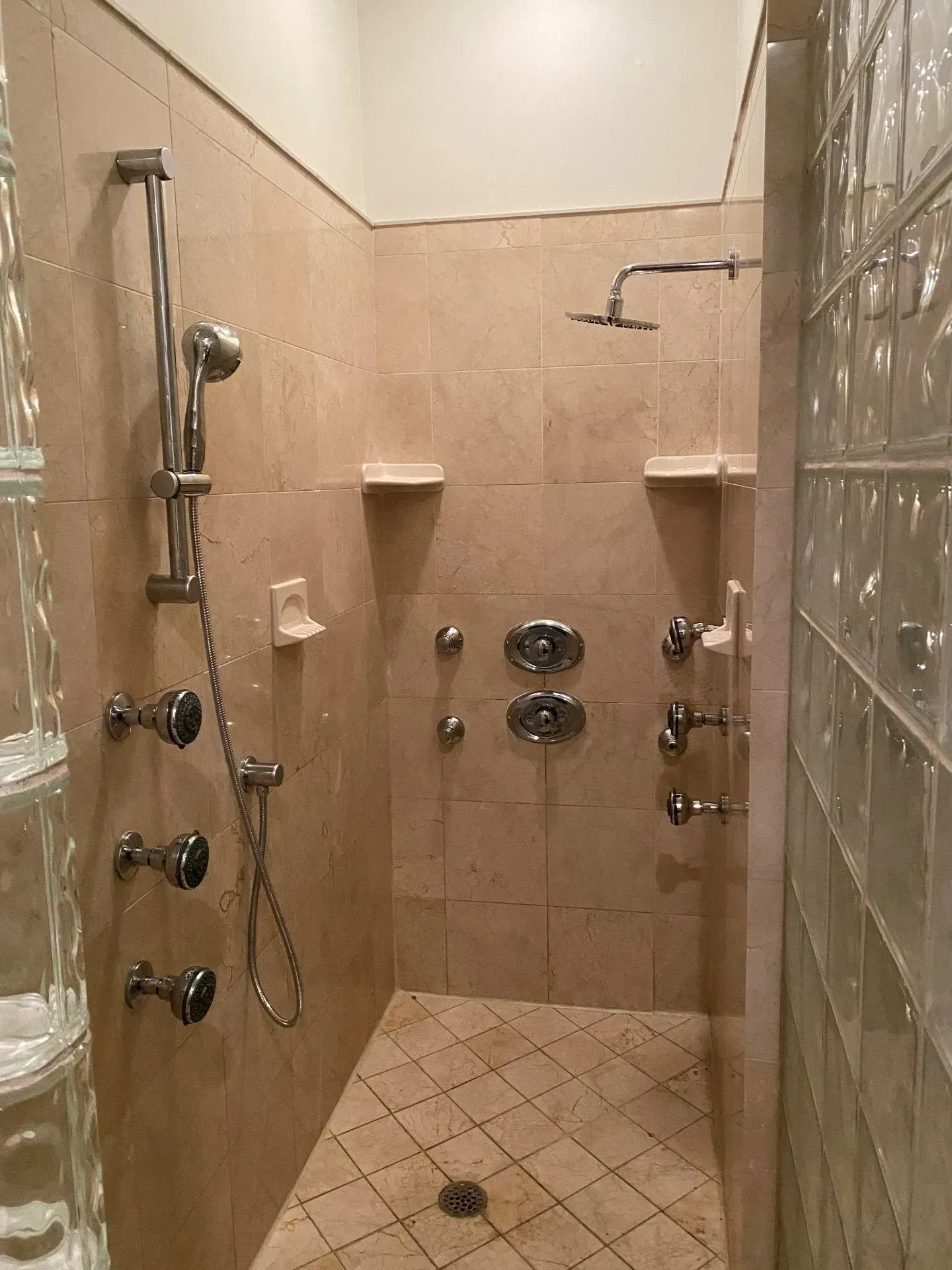 A bathroom with a walk-in shower and a glass block wall