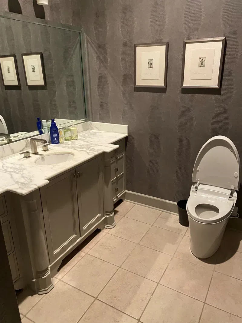 A bathroom with a toilet, sink, and white cabinet