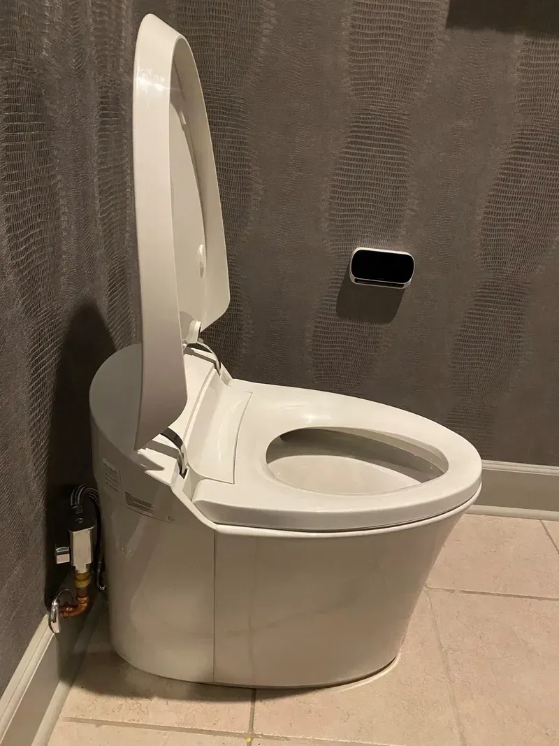 A white toilet is sitting in a bathroom next to a wall