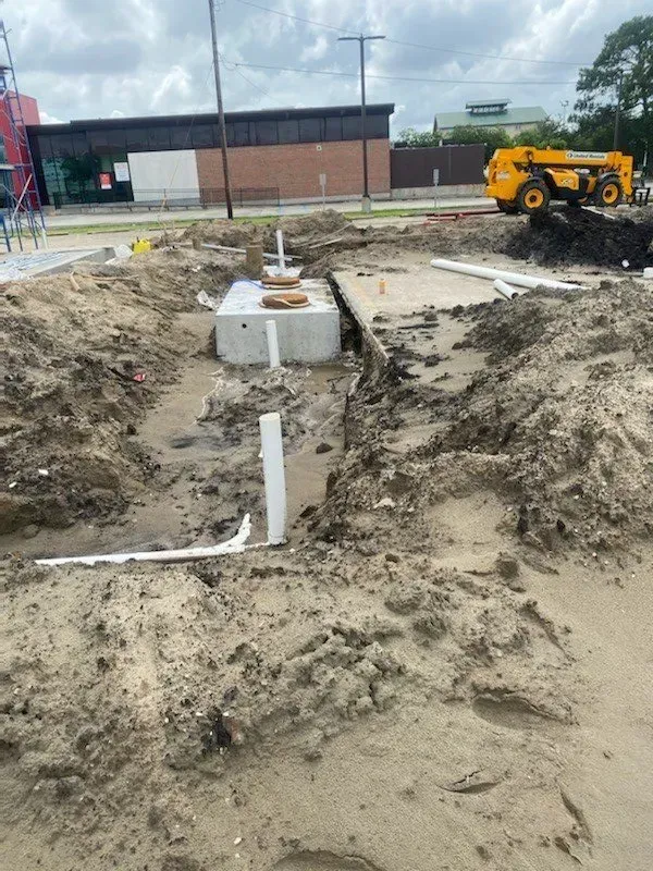 A construction site of a septic tank with a yellow bulldozer in the background