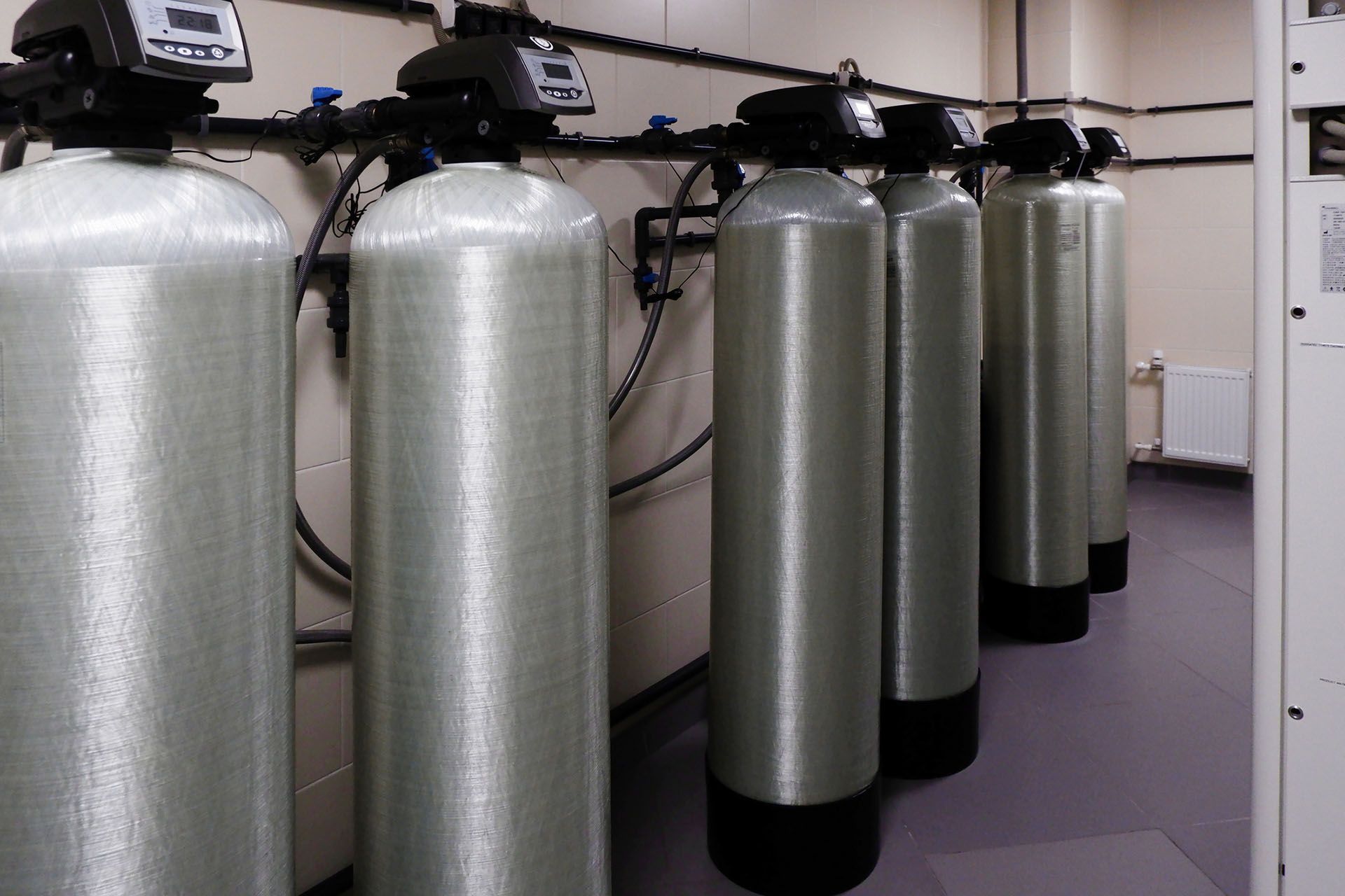 A row of water softeners are lined up in a room