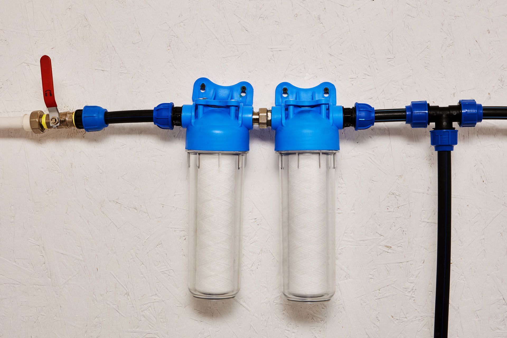 Two water filters are attached to a pipe on a wall