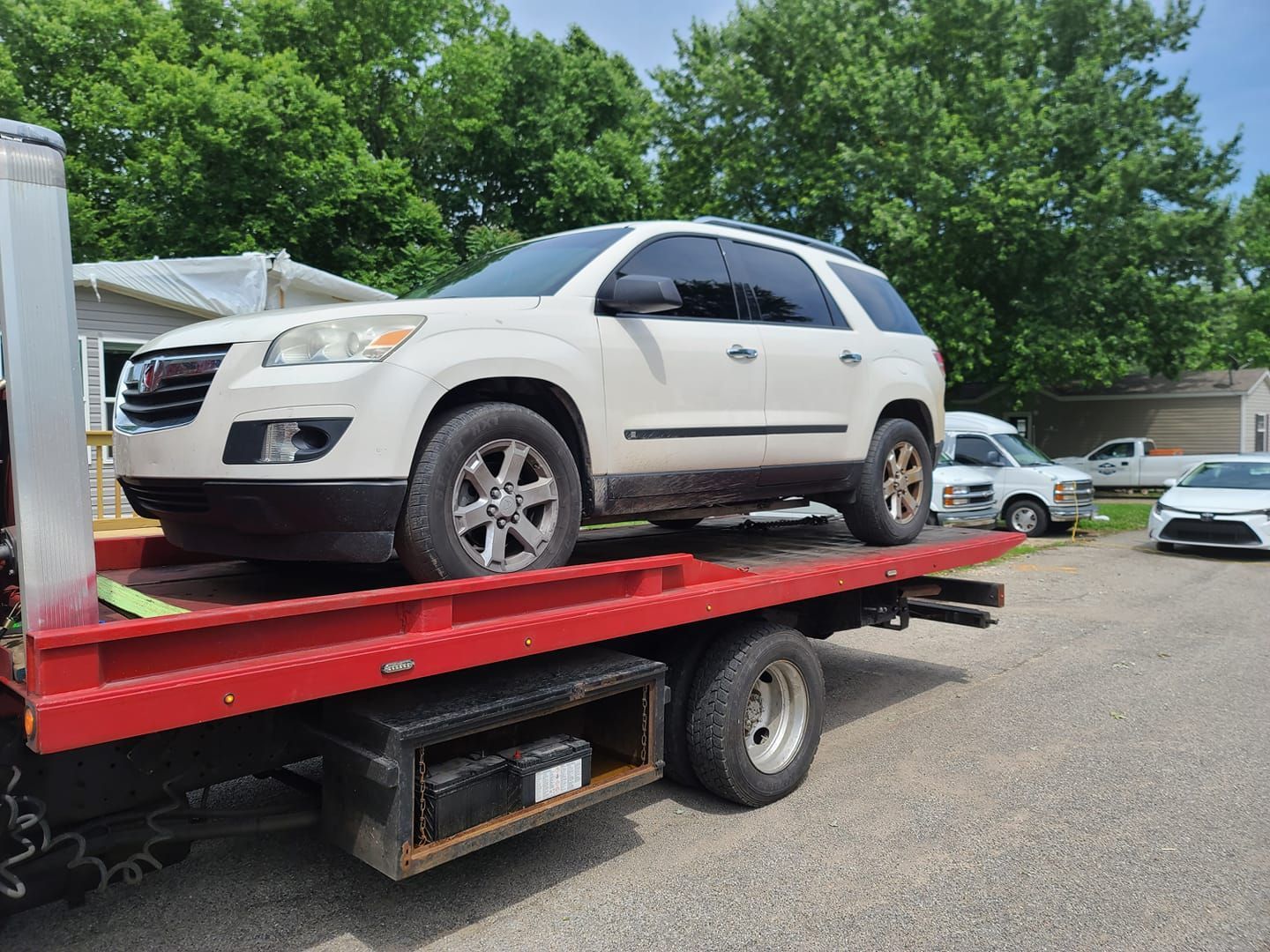 A white suv is sitting on top of a red tow truck.