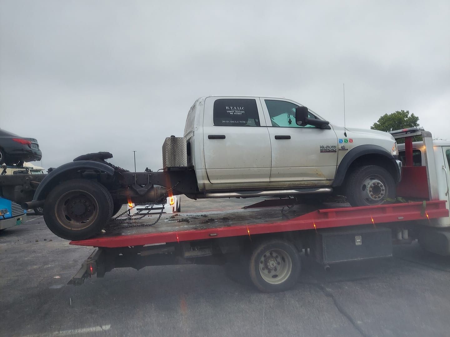 A white truck is sitting on top of a red tow truck.
