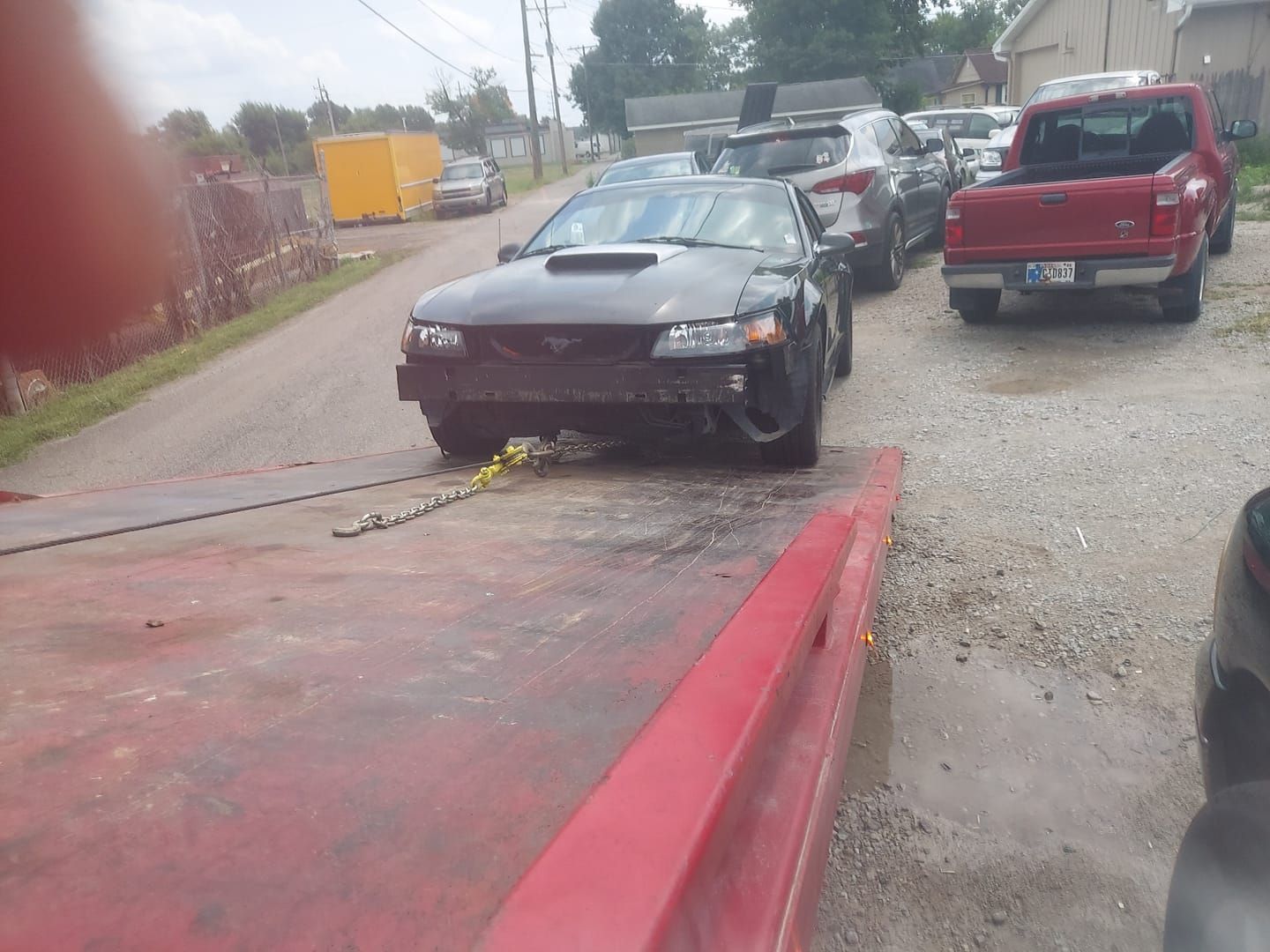 A black car is sitting on top of a red tow truck.