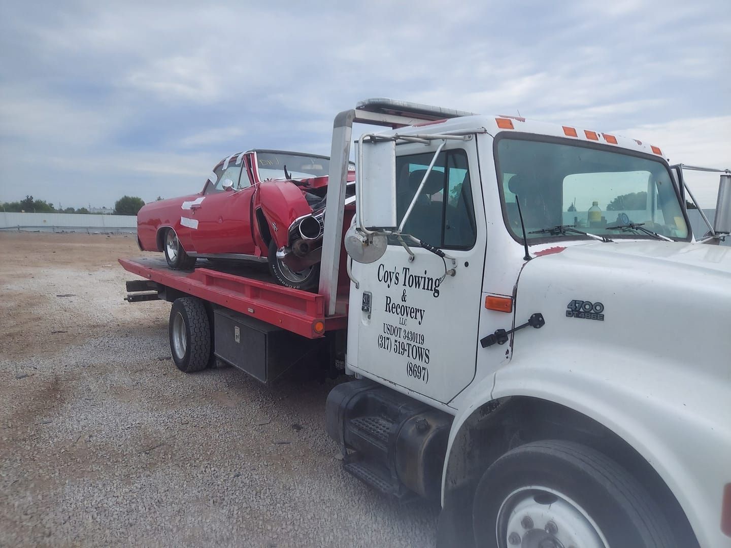 A tow truck with a red car on the back of it