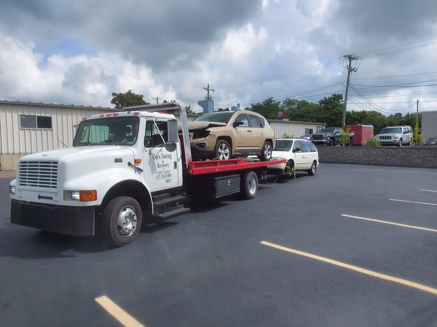 A tow truck is carrying a truck on the back of it
