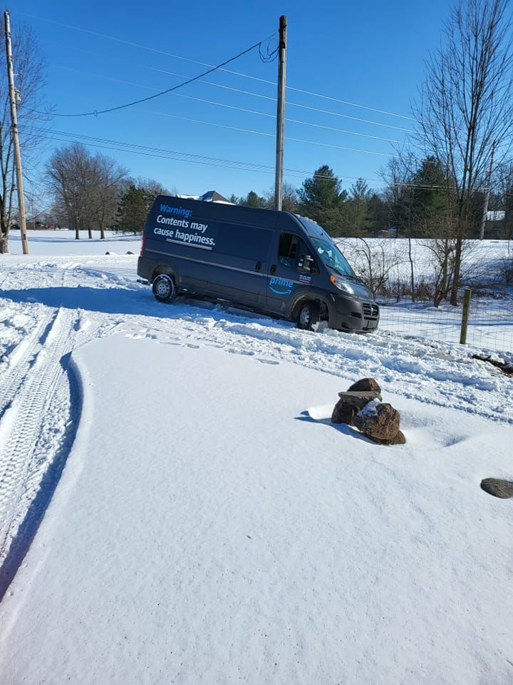A black van is driving down a snowy road.