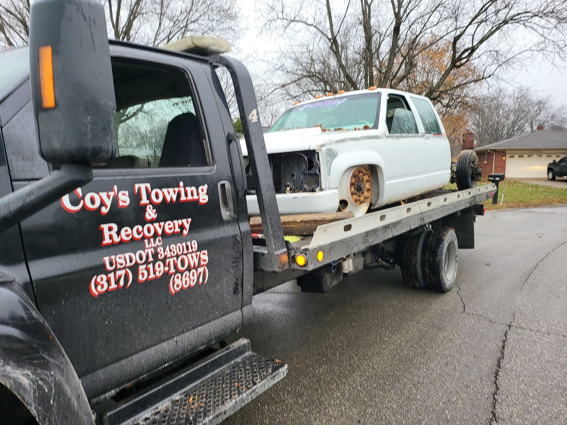 A tow truck with a white car on the back of it.