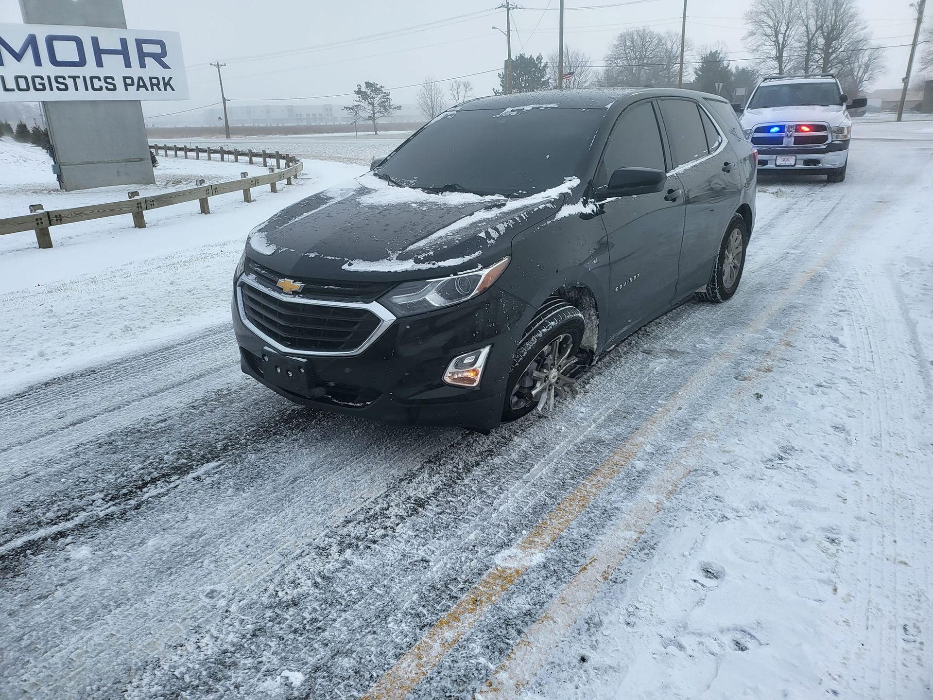 A black car is driving down a snowy road.