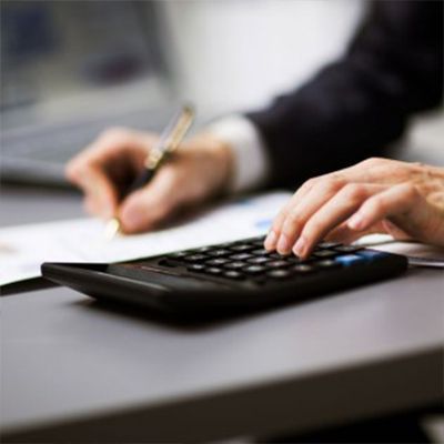 A person is using a calculator and writing on a piece of paper.
