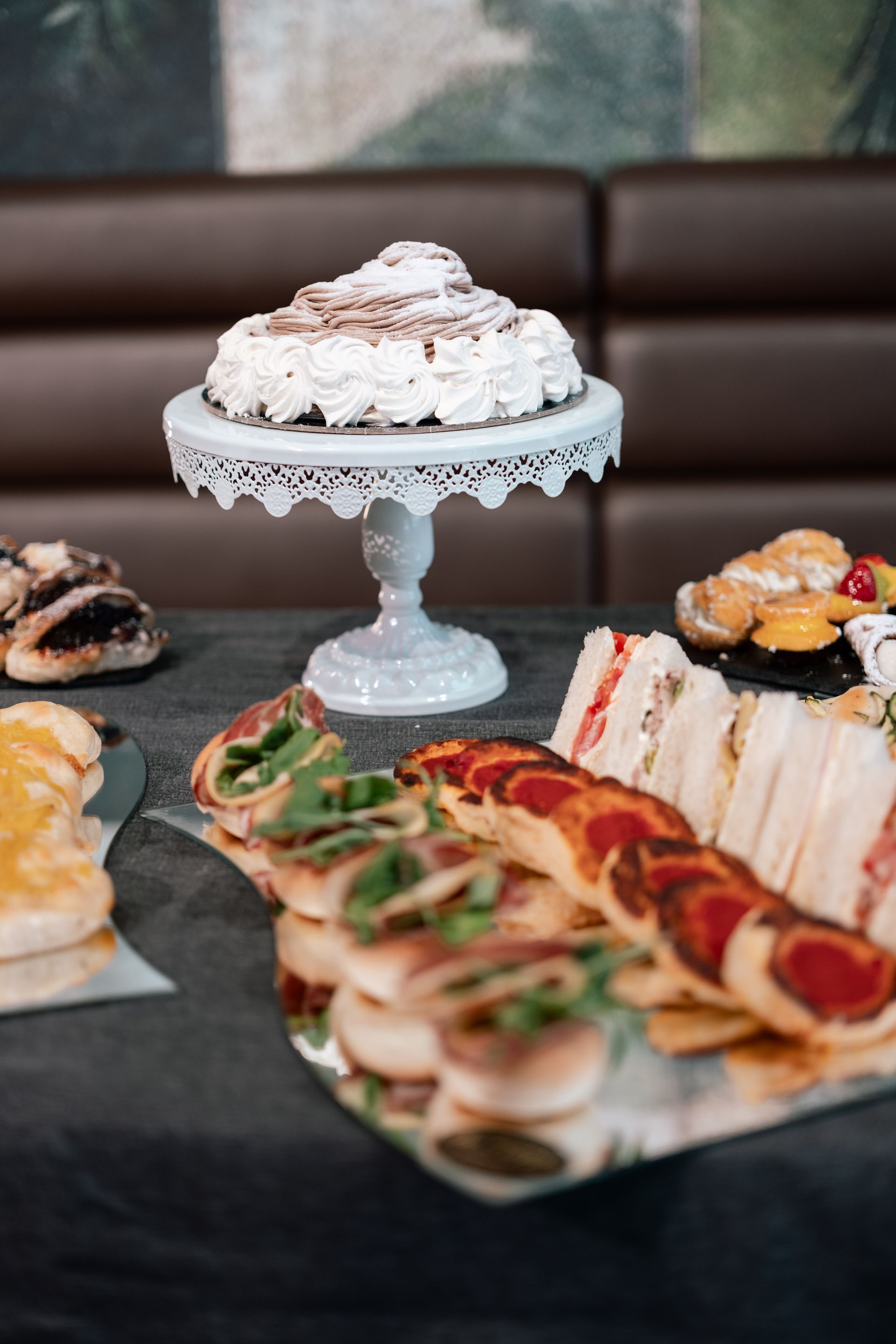 Buffet di dolci con torte e pasticcini disposti su un tavolo, tra cui spicca una torta glassata su un piedistallo.