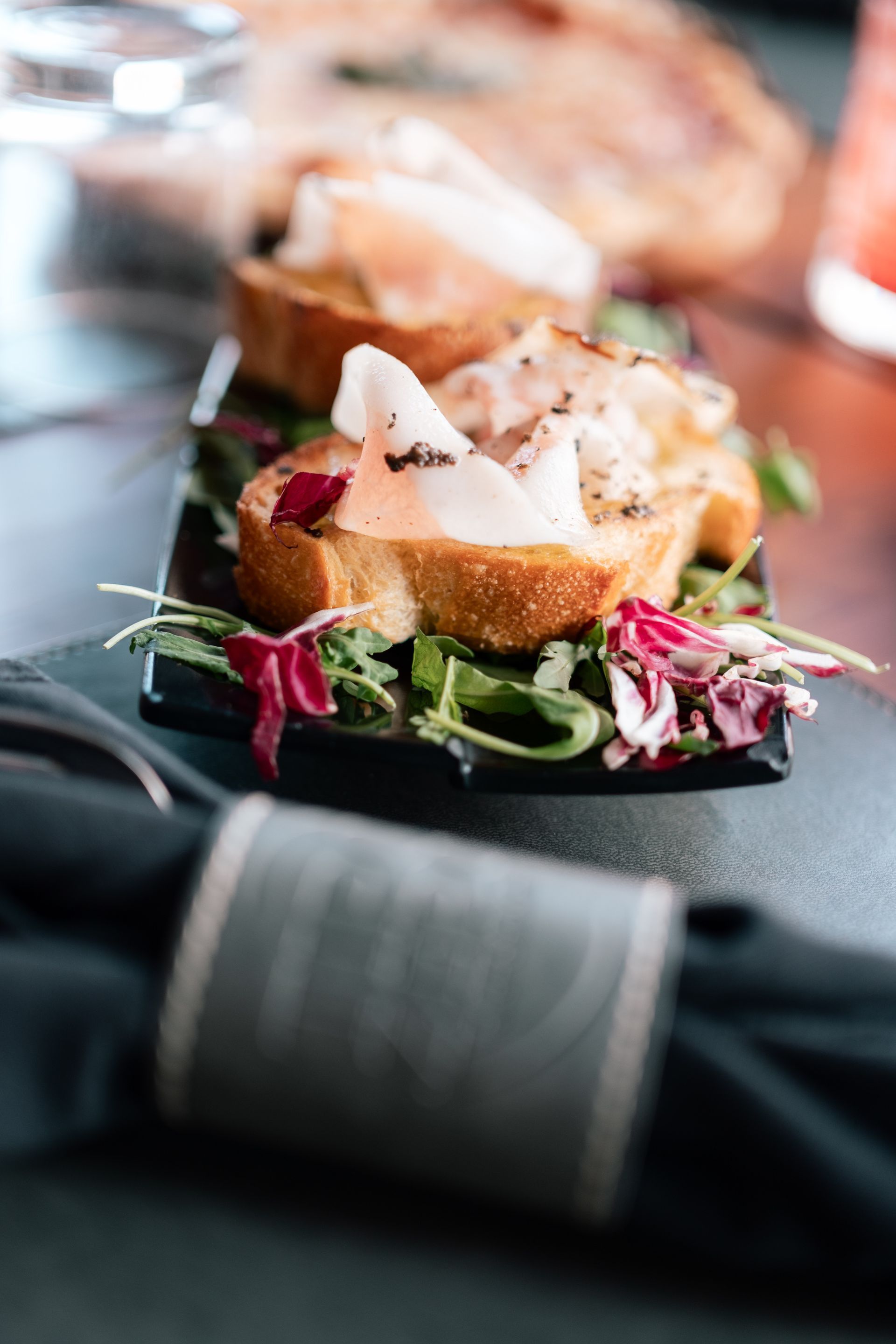 Panino gourmet con verdure su un tavolo scuro, leggermente sfocato sullo sfondo.