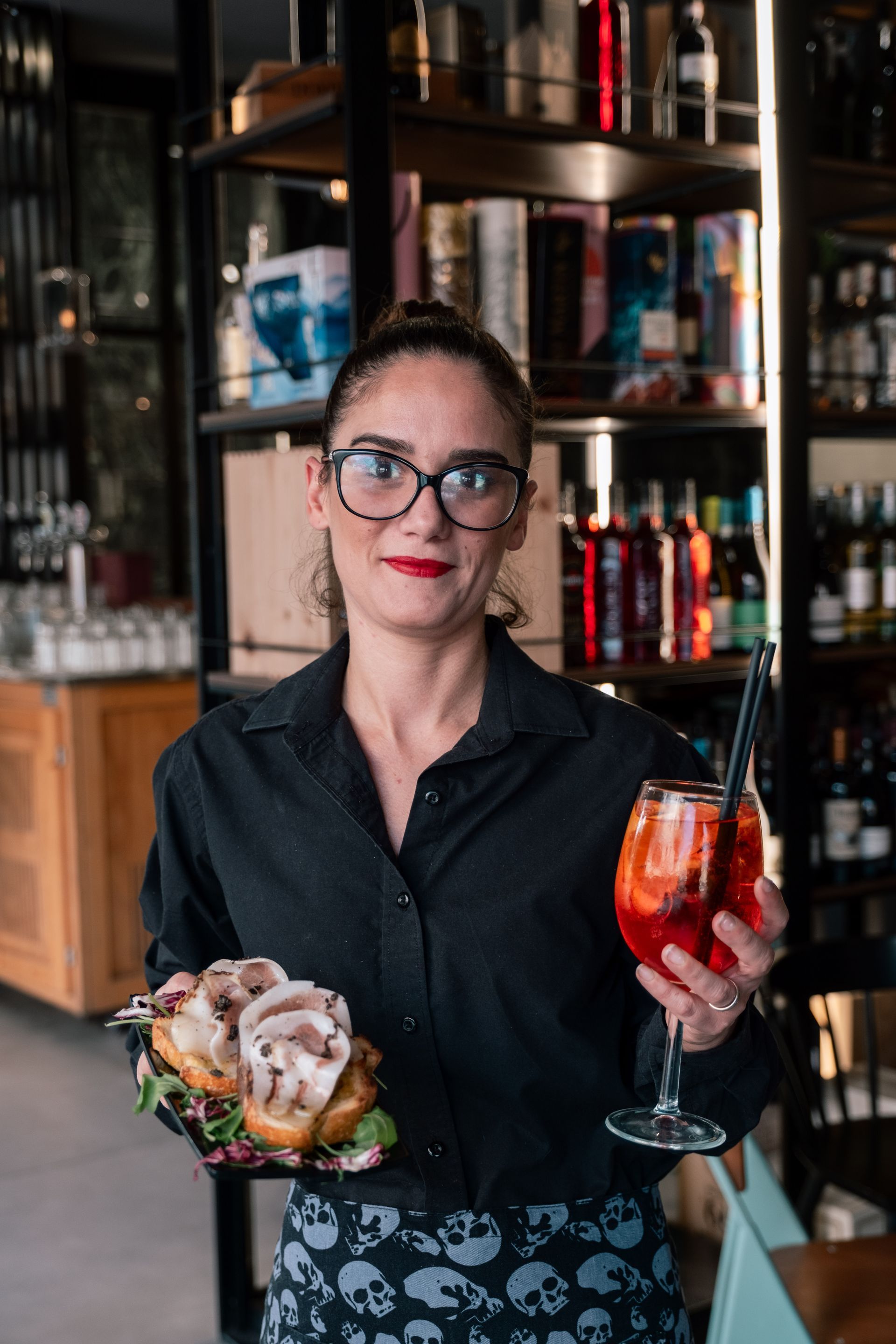 Un barista che tiene in mano un cocktail e un vassoio di ostriche in un bar elegante.