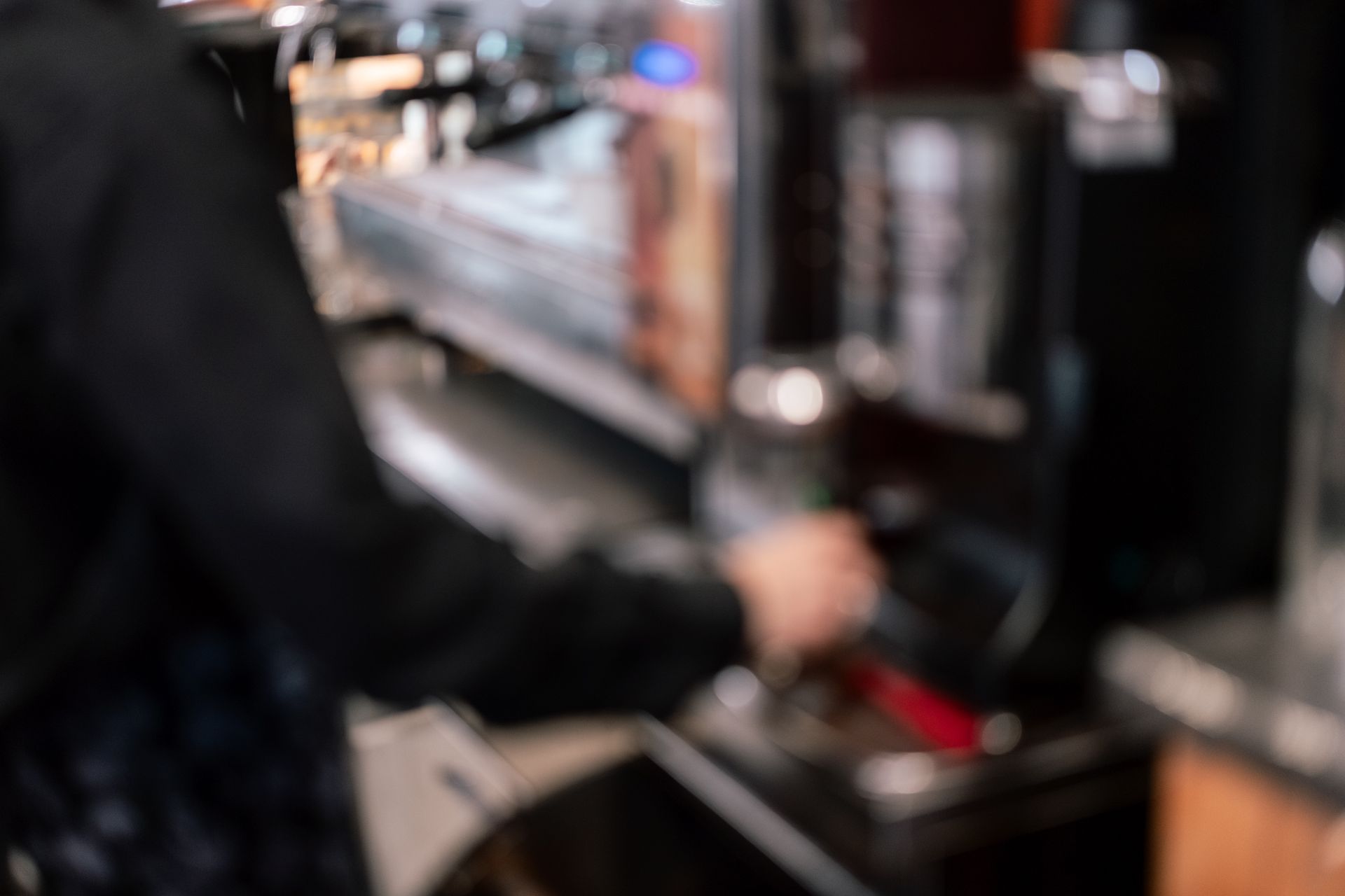 Barista che utilizza una macchina per espresso in una caffetteria scarsamente illuminata.