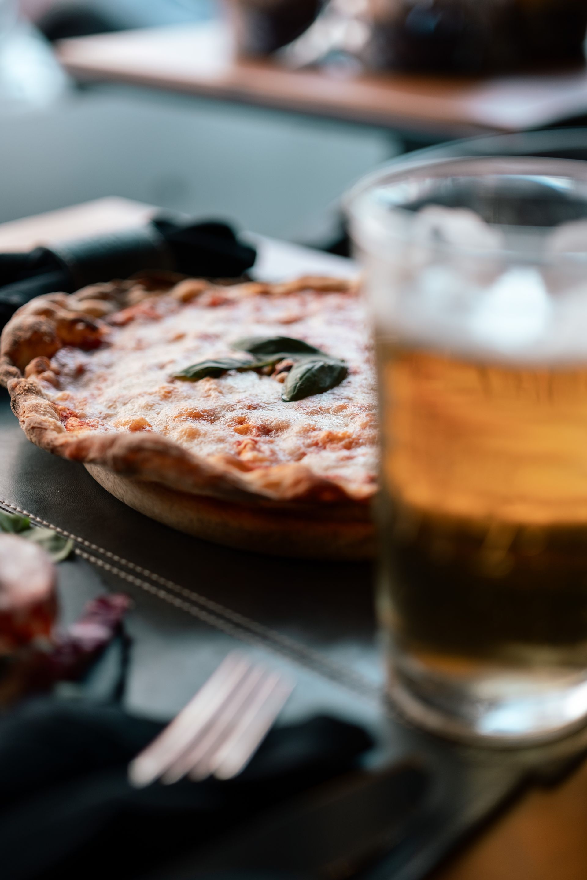 Pizza e birra su un tavolo in un ristorante illuminato da luci soffuse.