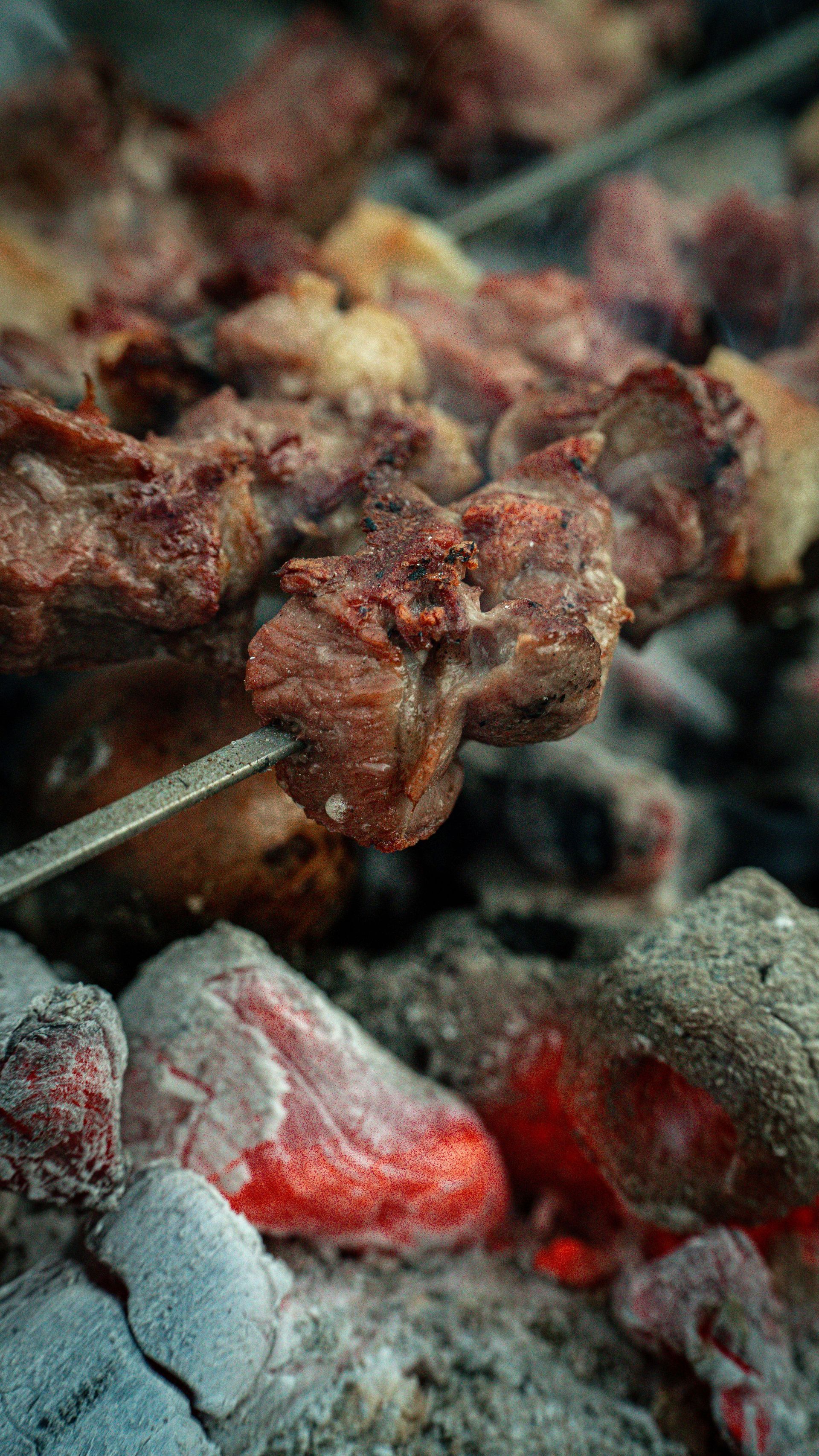 Carne grigliata su spiedini che sfrigola sulle braci ardenti.