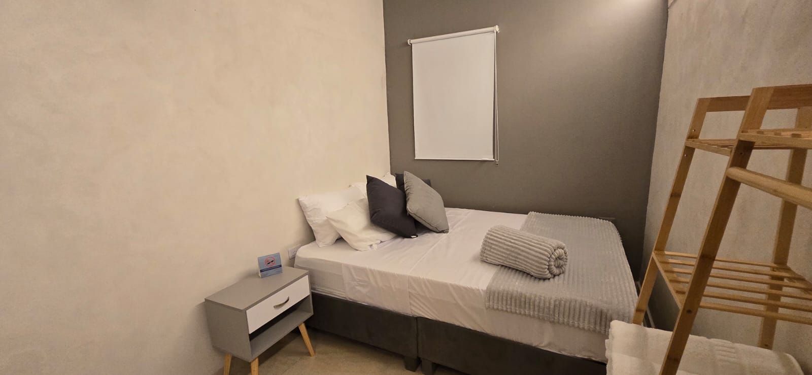 Two beds in a white room with art prints. Black and pink pillows on white bedding.