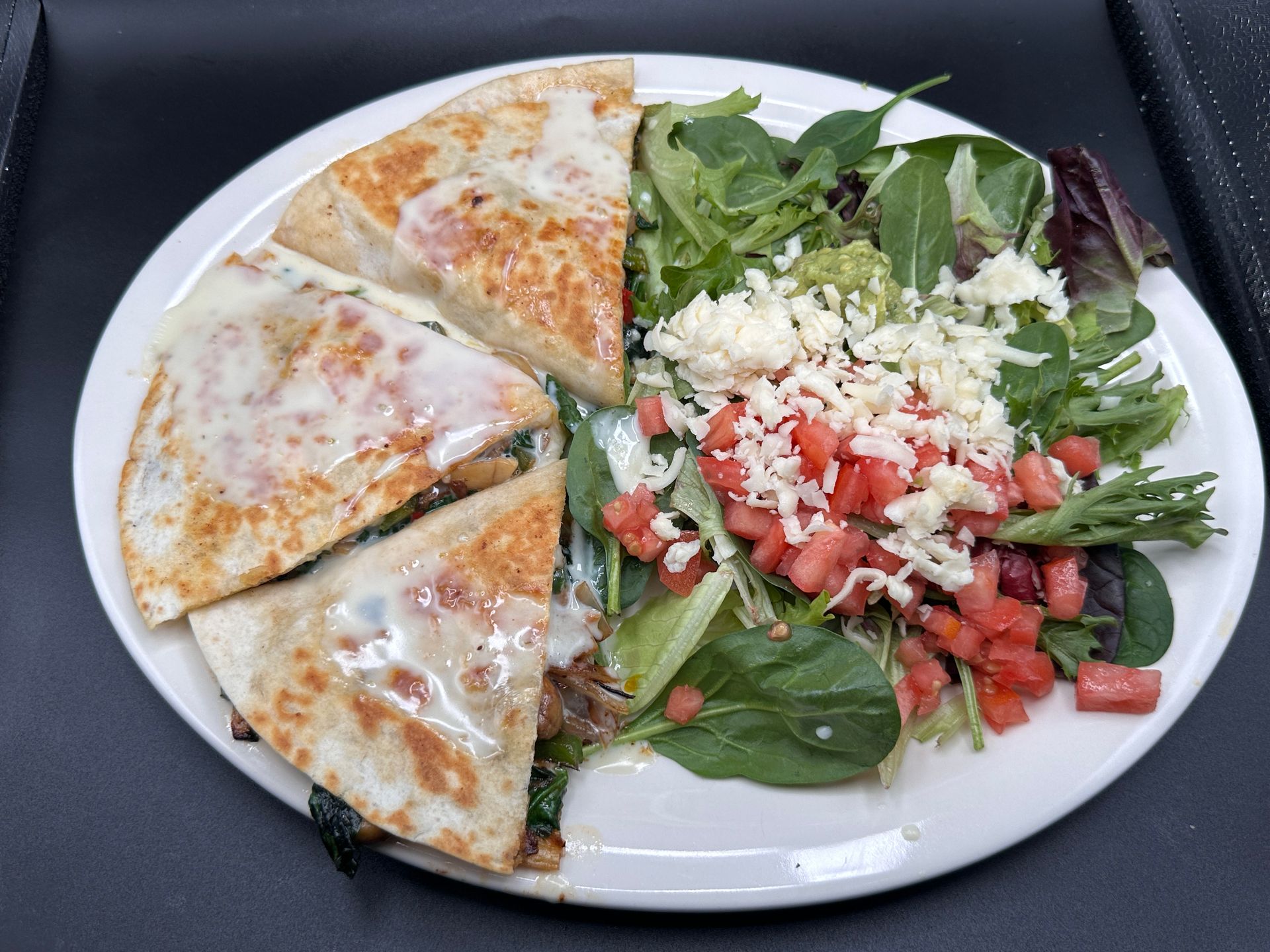 Quesadilla slices with melted cheese and side salad with tomatoes and cheese.
