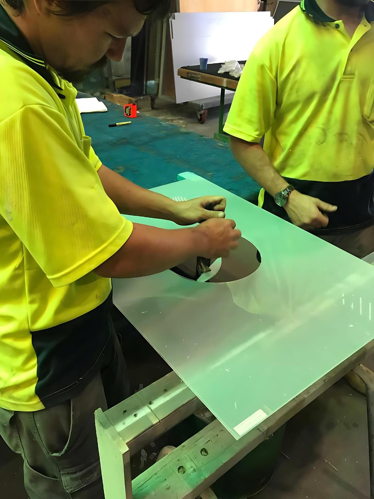 Two Men in Yellow Shirts Are Working on a Piece of Glass — Cessnock Glass in Cessnock, NSW
