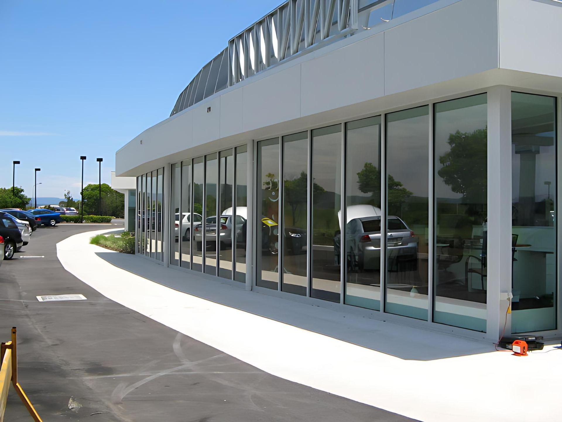 A Building With a Lot of Windows and Cars Parked in Front of It — Cessnock Glass in Cessnock, NSW