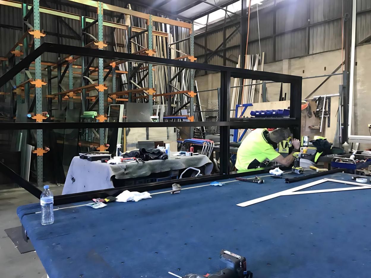 A Man is Working on a Piece of Metal in a Warehouse — Cessnock Glass in Newcastle, NSW