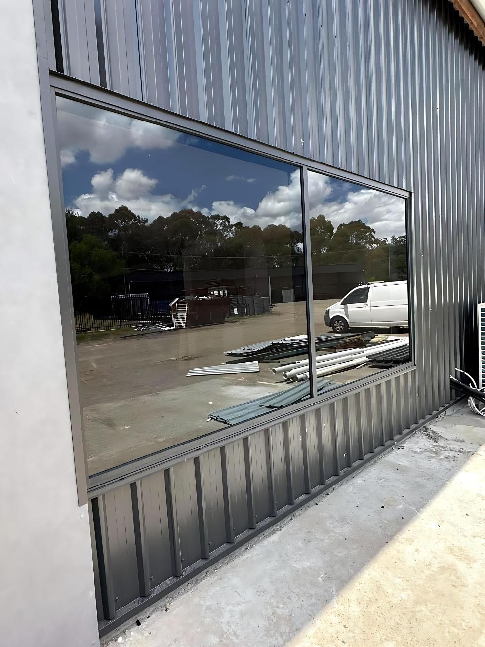 A Large Window on the Side of a Building With a Van Parked in Front of It — Cessnock Glass in Lake Macquarie, NSW