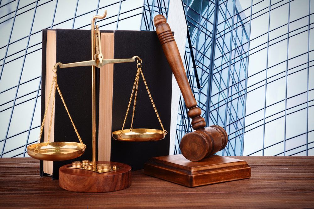 Gavel with books and scales on modern skyscraper background — Solicitors in Cessnock, NSW