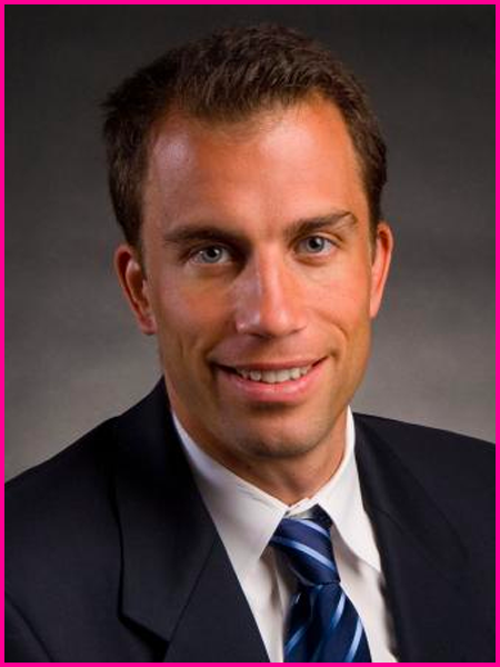 A man in a suit and tie is smiling for the camera