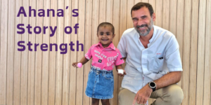 A man and a little girl are sitting in front of a wooden wall.