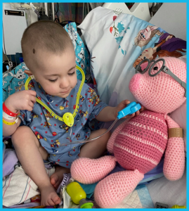 A baby is playing with a stuffed pig and a stethoscope
