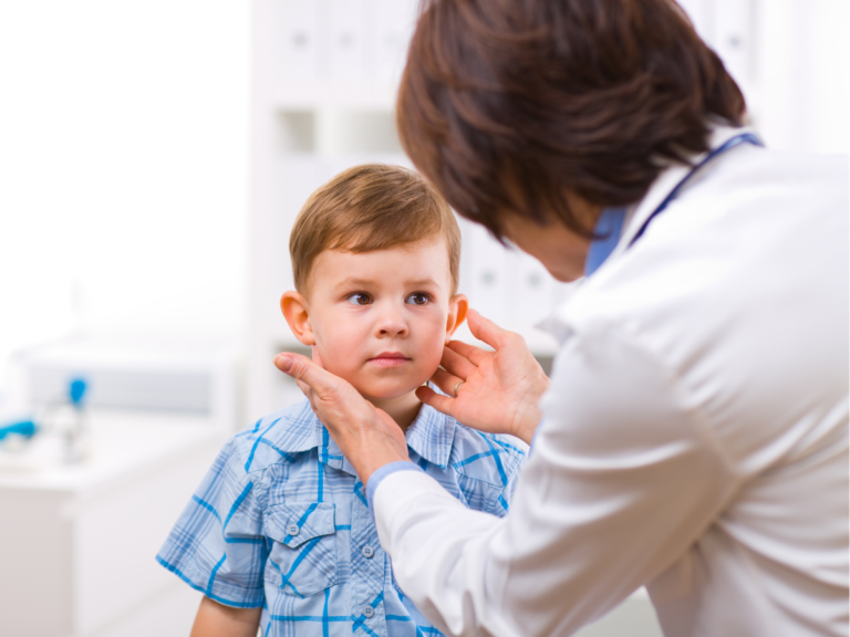 A doctor examines a young boy 's ear in a hospital.