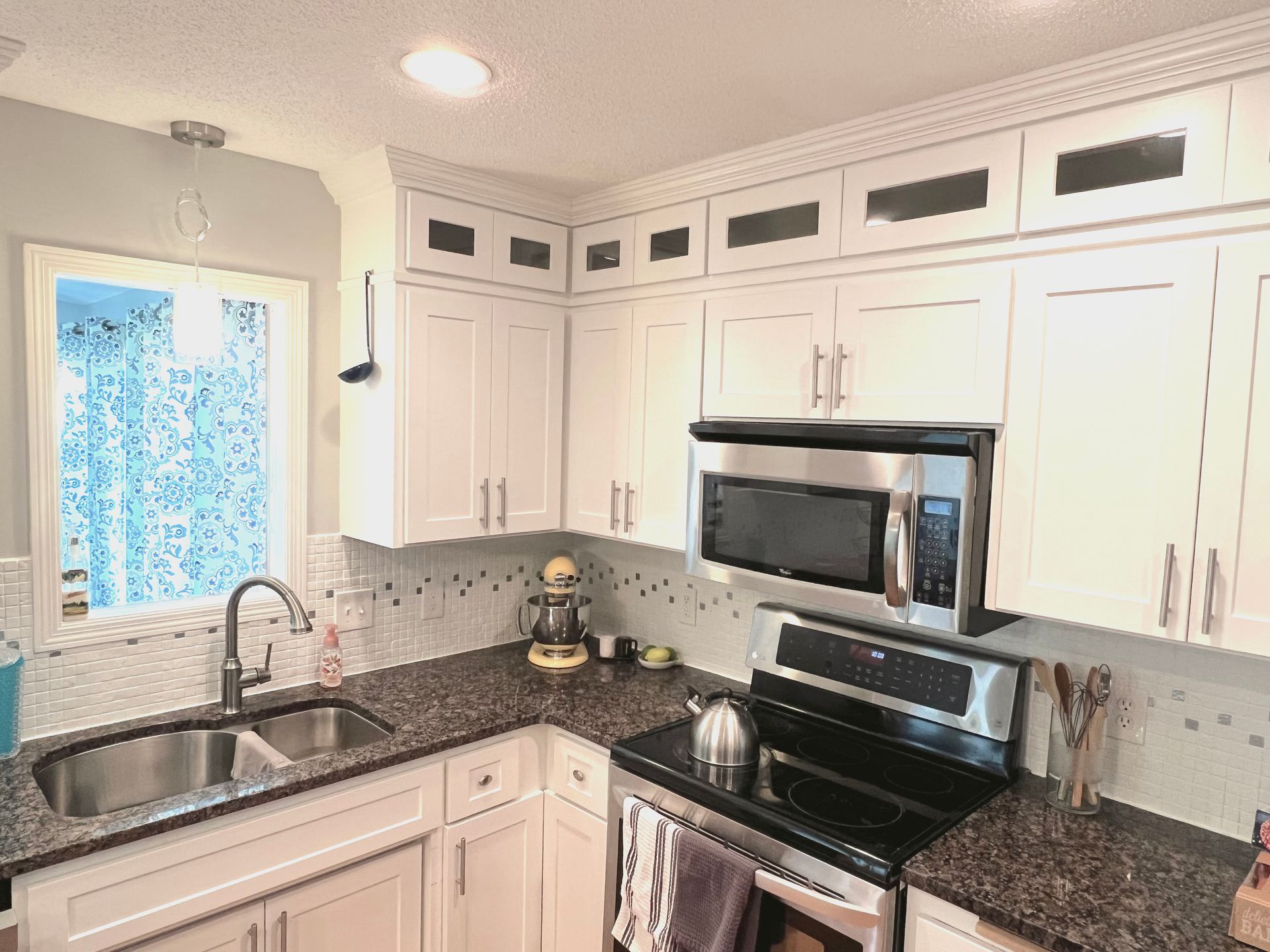 A kitchen with white cabinets , stainless steel appliances , granite counter tops and a sink. A kitchen with white cabinets , stainless steel appliances , granite counter tops and a sink.