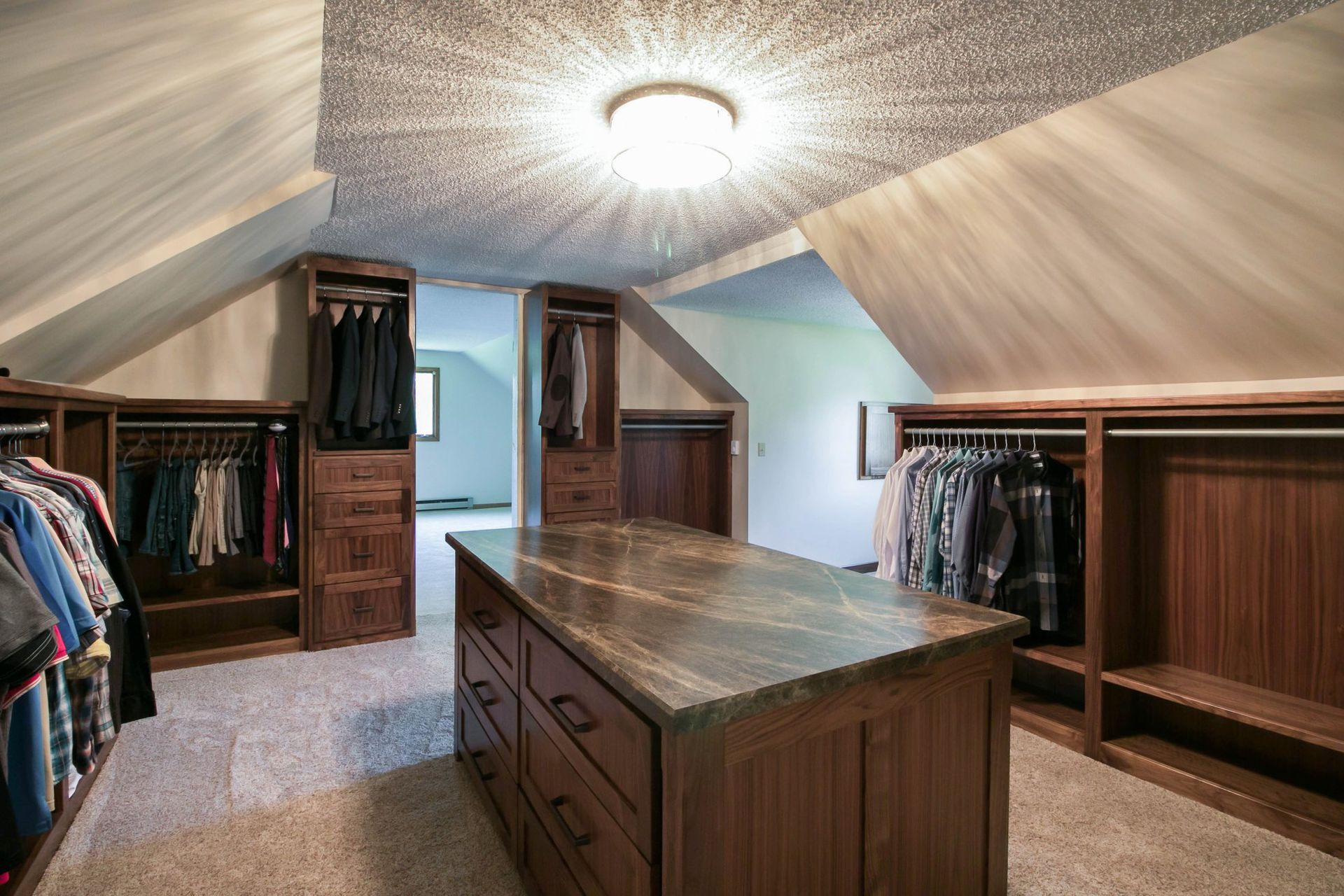 A walk in closet with a large island in the middle A walk in closet with a large island in the middle