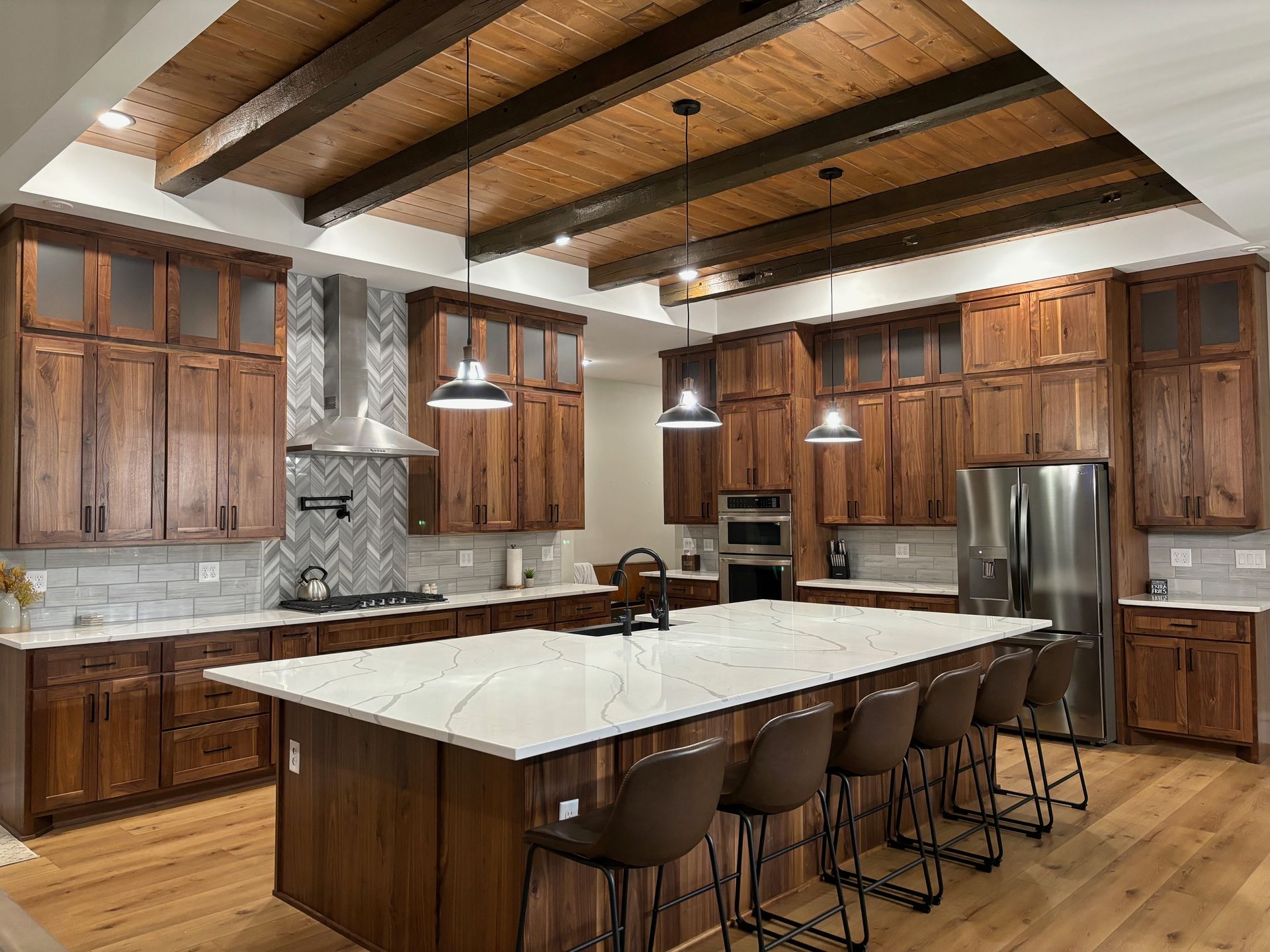 A kitchen with wooden cabinets , stainless steel appliances , and a large marble island.