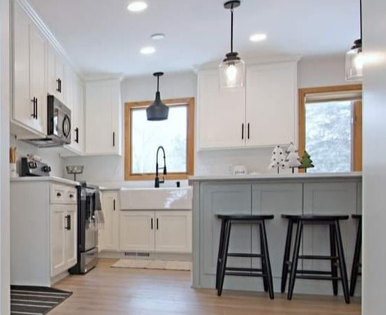 White Casa Collection kitchen with light gray island, black hardware, and pendant lighting.