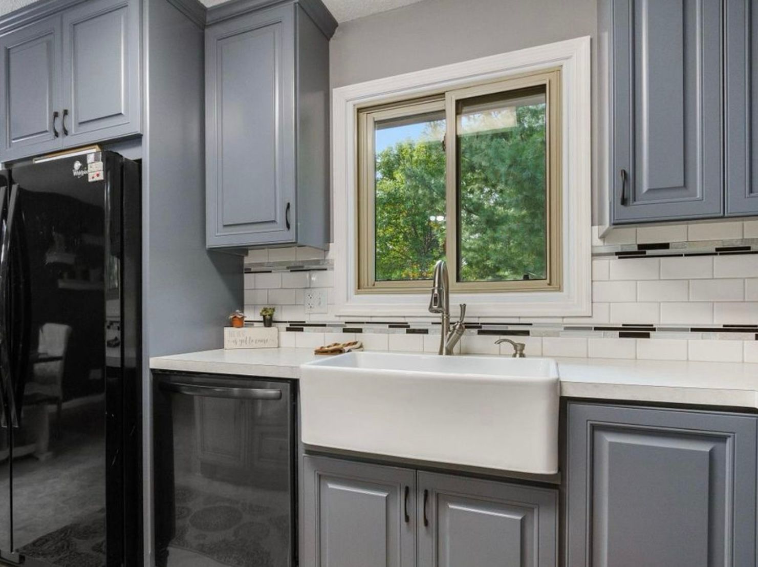 Gray kitchen cabinetry surrounding a white farmhouse sink in Blaine, Minnesota.