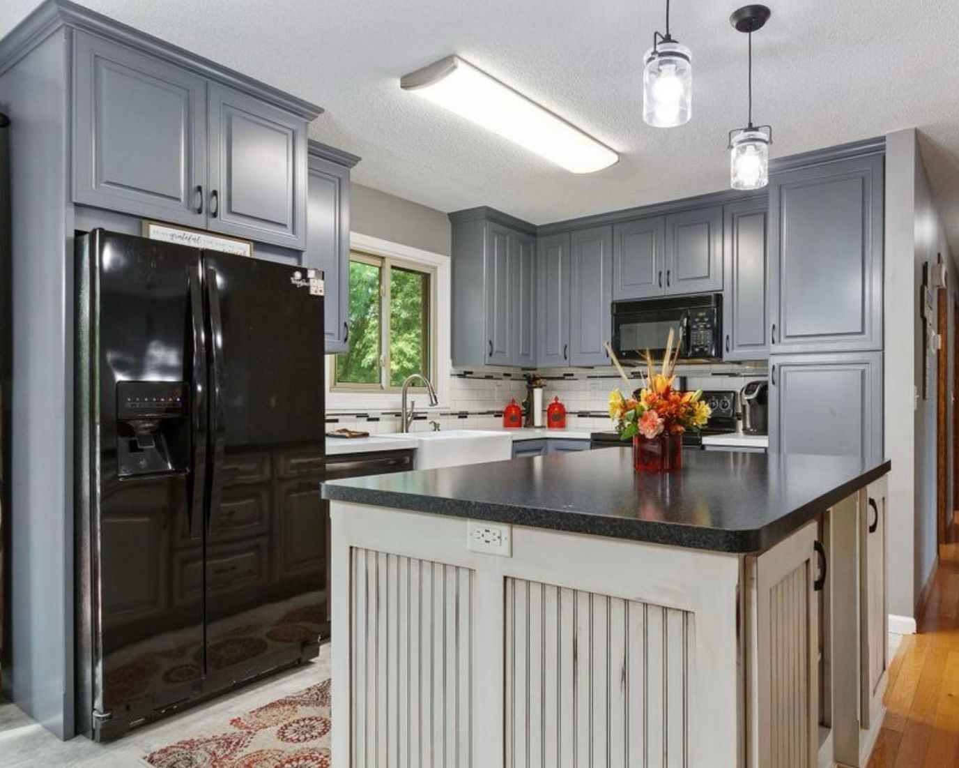 Custom gray kitchen cabinetry with rustic island and beadboard detailing in Blaine, Minnesota.