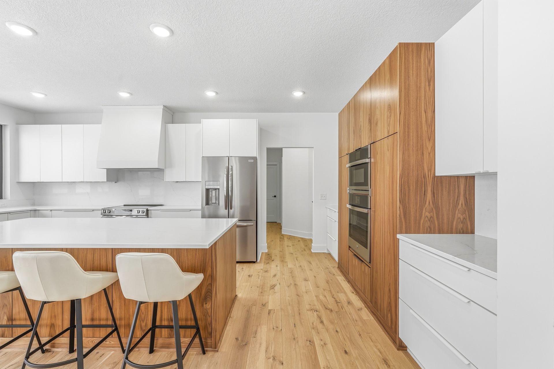 White and walnut Signature Collection kitchen with custom walnut appliance cabinetry and large island in Centerville, Minnesota.